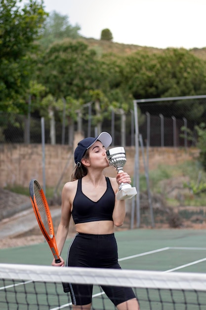 Young woman happy kissing his new award won on a sport tournament wearing black sportswear