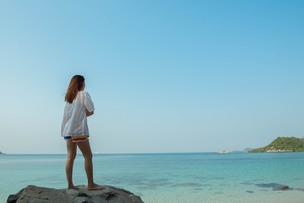 Young woman happy standing on the rock at the beach