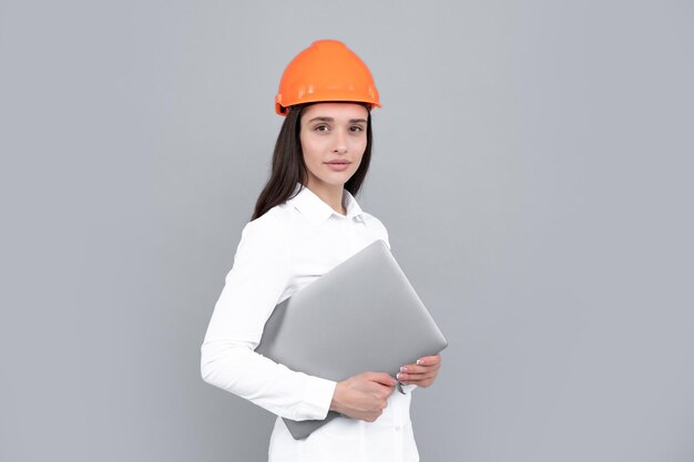 Young woman in hard hat helmet with laptop computer isolated on grey background Architect woman wear helmet and shirt Business woman construction manager builder