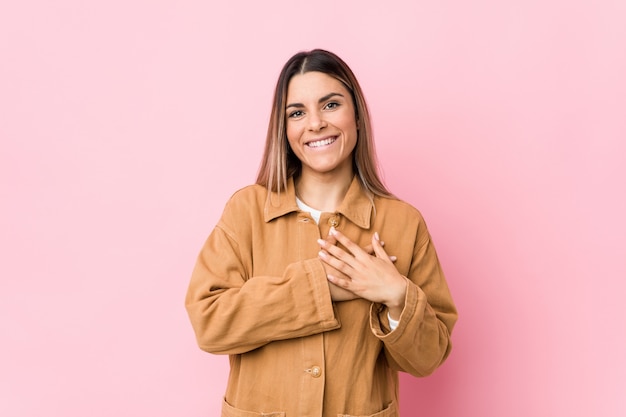 Young woman has friendly expression, pressing palm to chest