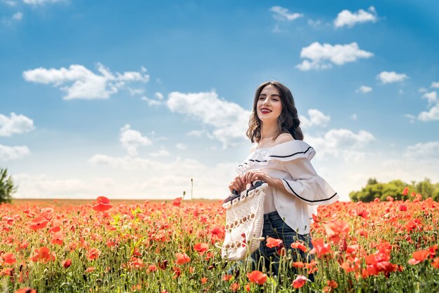 Young woman in hat walk at poppy field pick flowers. summer time