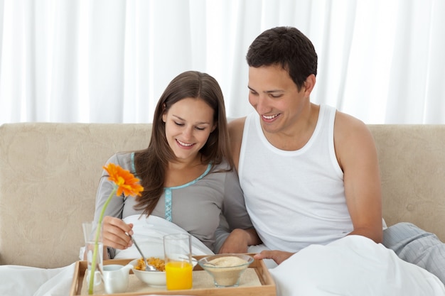 Young woman having breakfast on the bed with her boyfriend 