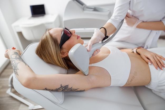 Young woman having laser hair removal procedure in cosmetology clinic