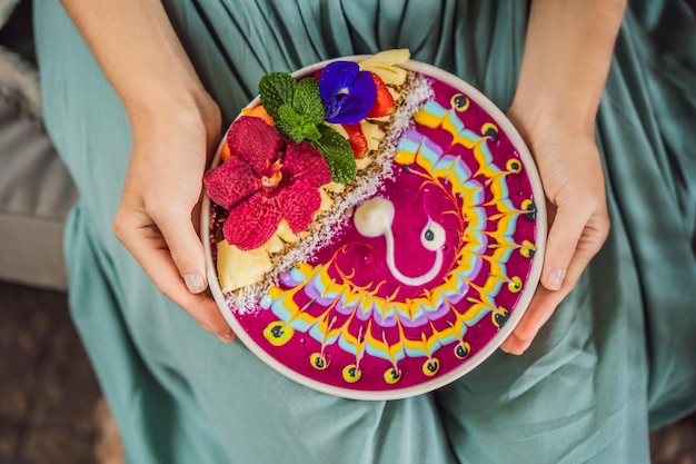 Young woman having a mediterranean breakfast seated at her sofa and eats healthy tropical breakfast