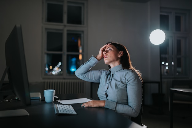 Young woman having a migraine while working overtime.