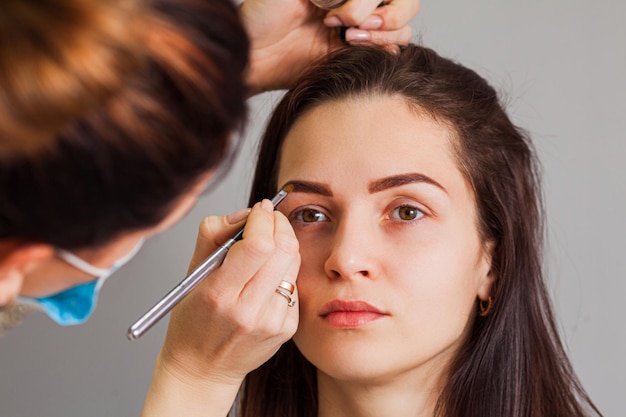 Young woman having professional eyebrow correction procedure in beauty salon