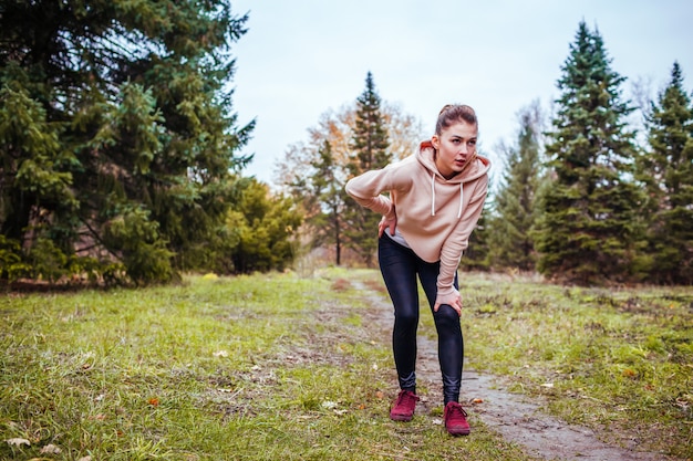 Young woman having rest after a run in autumn forest