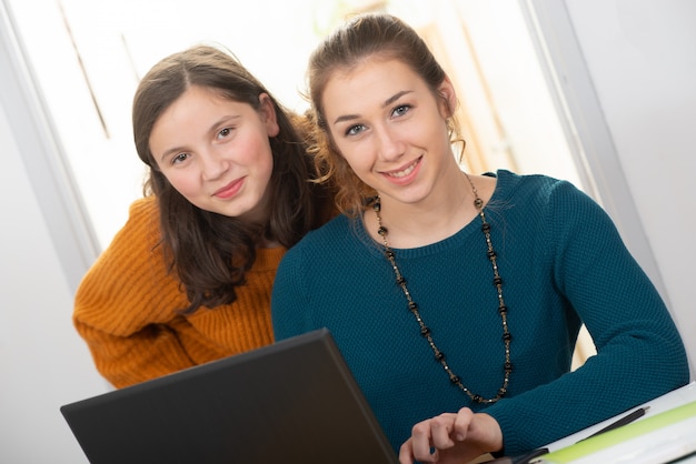 Young woman helps a teen girl with  homework