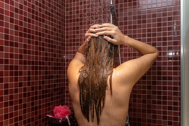 Young woman on her back in the shower washing her head. Concept of woman's beauty and personal care.