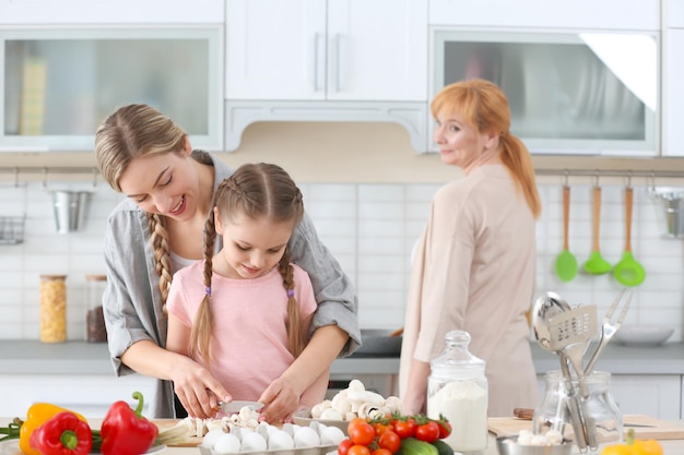 Young woman her daughter and mother cooking in kitchen