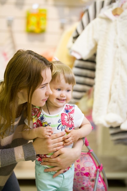 Young woman and her daughter smiling at the childrens clothes shop