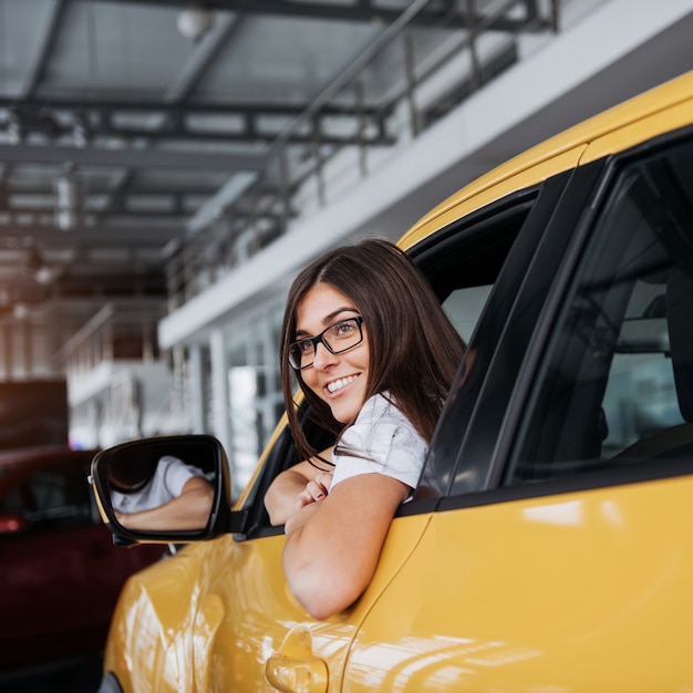 Young woman in her new car smiling