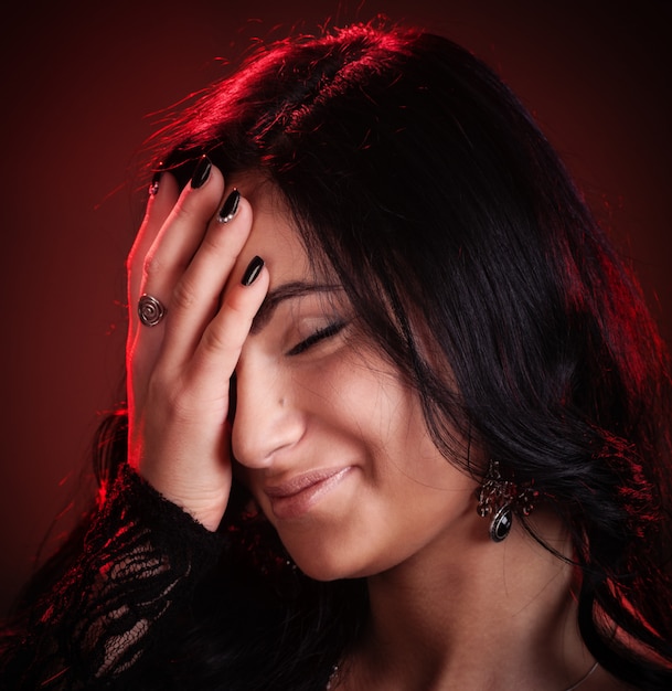 Young woman hides her face by hand