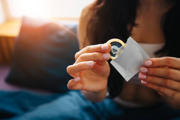 Young woman hold condom in hand. Sexual safety