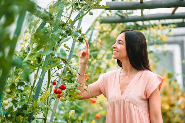 Young woman holding a basket of greenery and onion in the greenhouse