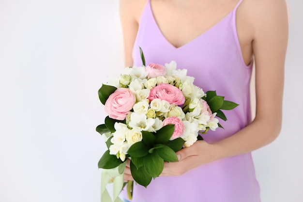 Young woman holding beautiful bouquet with freesia flowers on white background