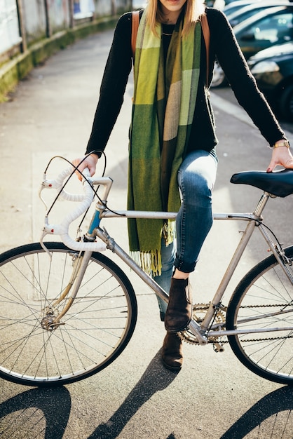 young woman holding a bicycle outdoor in the city