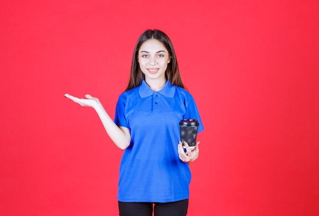 Young woman holding a black disposable coffee cup