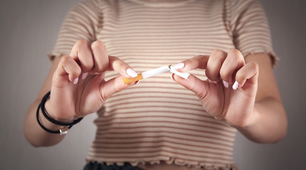 Young woman holding a broken cigarette. Quit smoking