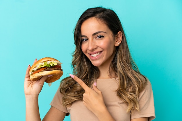 Young woman holding a burger over isolated background