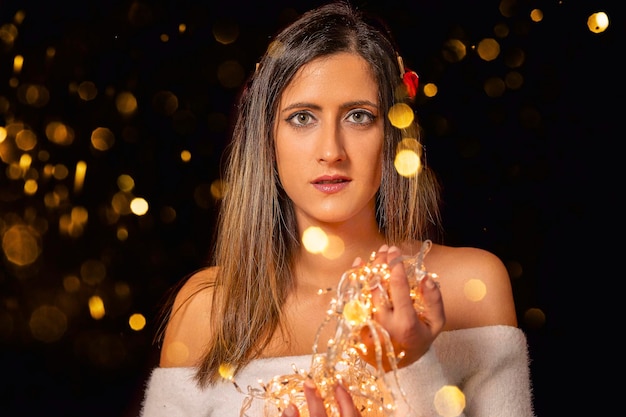 Photo young woman holding christmass string lights