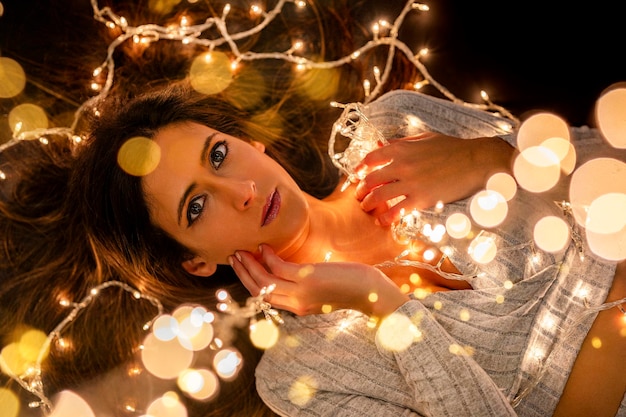 Photo young woman holding christmass string lights