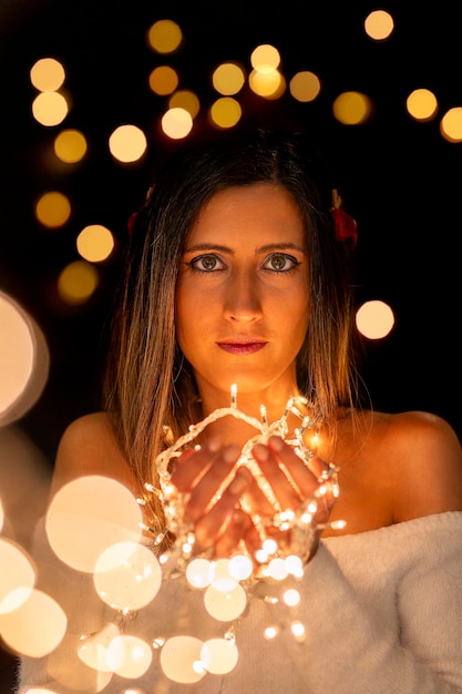 Photo young woman holding christmass string lights