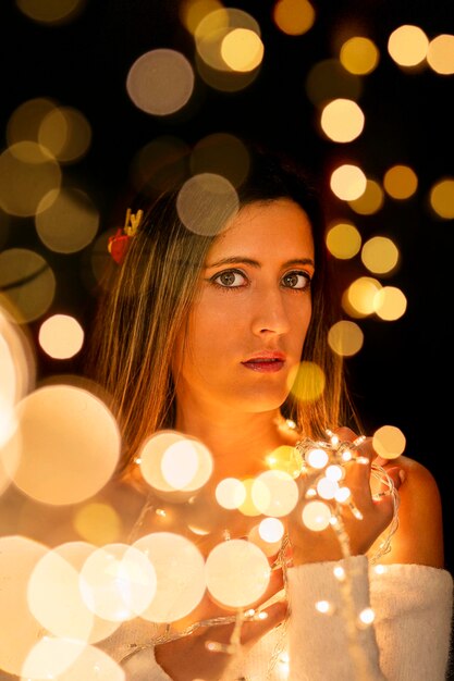 Photo young woman holding christmass string lights