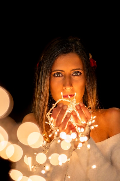 Photo young woman holding christmass string lights