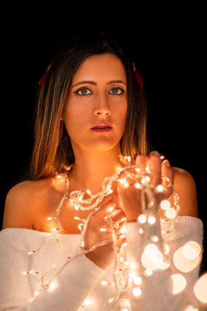 Photo young woman holding christmass string lights