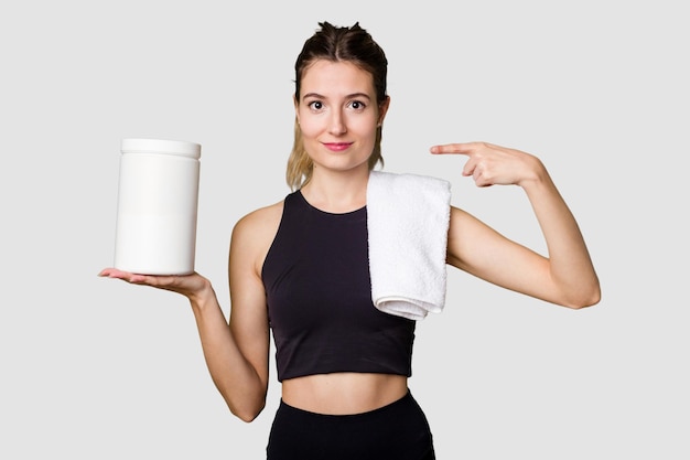 Young woman holding a container of protein powder dressed in sportswear