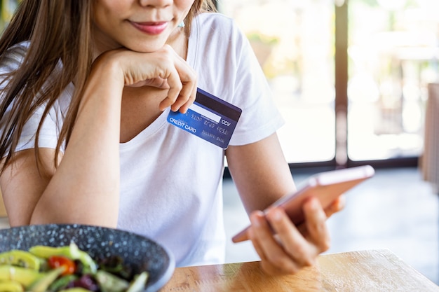 Young woman holding a credit card and smartphone