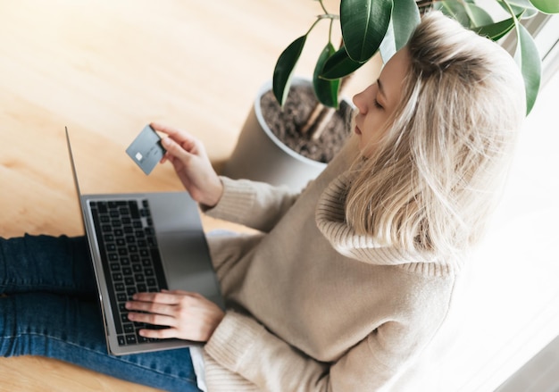 Young woman holding credit card and using laptop computer