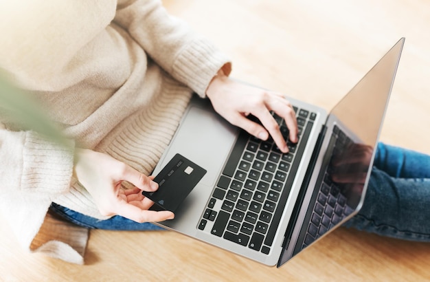 Photo young woman holding credit card and using laptop computer