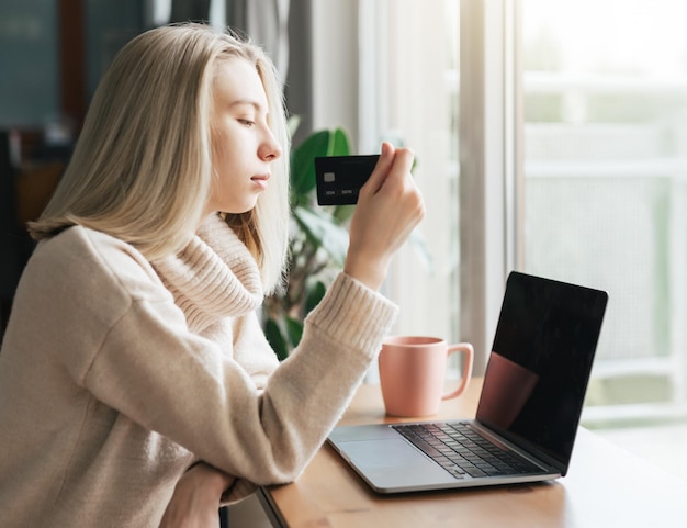 Young woman holding credit card and using laptop computer