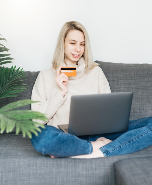 Photo young woman holding credit card and using laptop computer