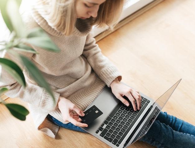 Young woman holding credit card and using laptop computer