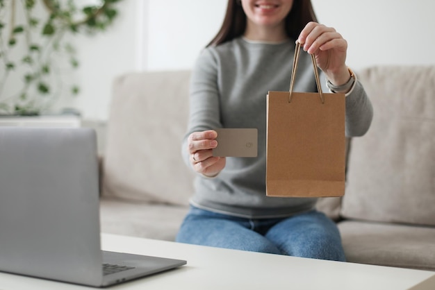 Young woman holding credit card and using laptop at home Paying online home shopping internet banking electronic store concept