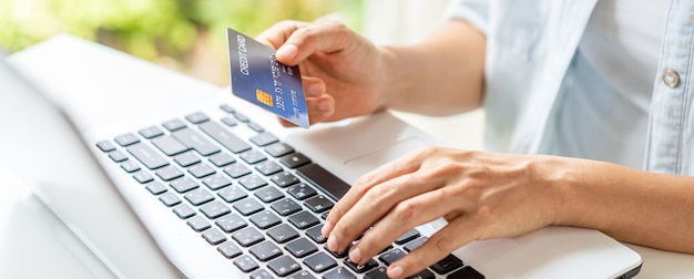 Young woman holding a credit card and using laptop