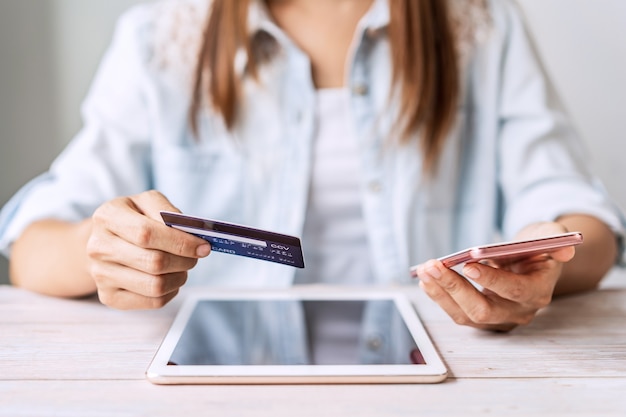 Young woman holding a credit card and using phone