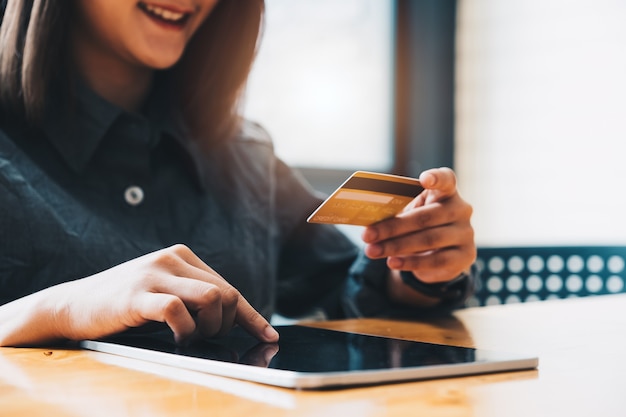 Young woman holding credit card and using tablet computer. Online shopping concept.