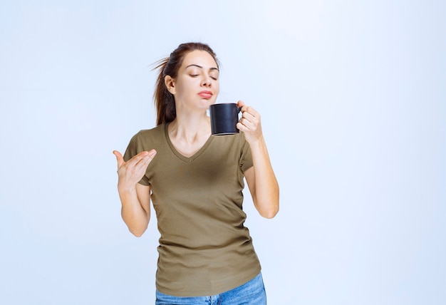 Young woman holding a cup of drink and pointing at it