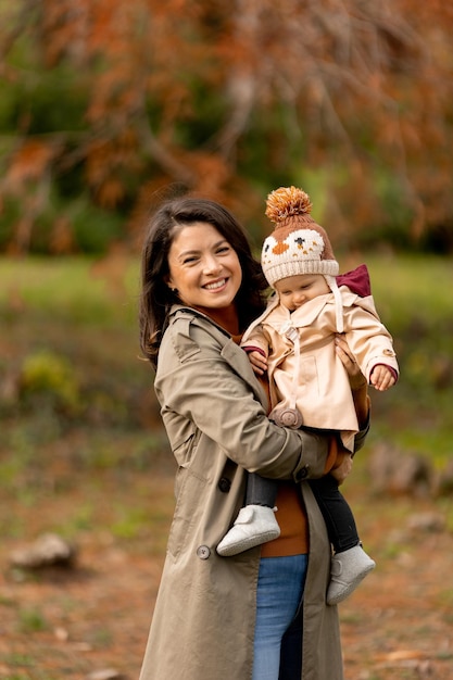 Young woman holding cute baby girl in the autumn park