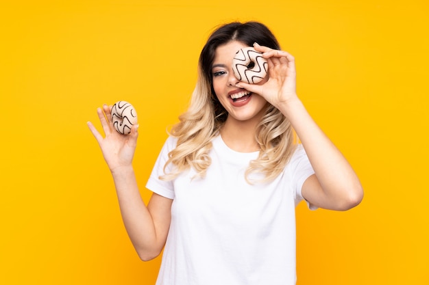 Young woman holding a donut over isolated