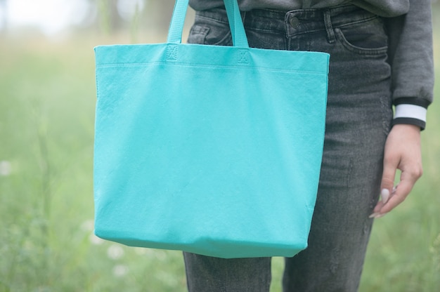 Young woman holding emerald green shopper bag, no face, eco lifestyle concept