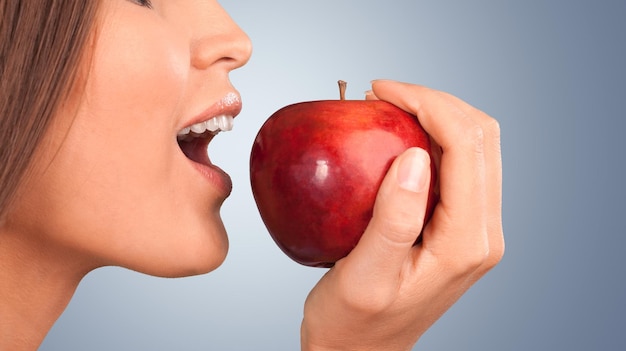 Young woman holding fresh apple on background