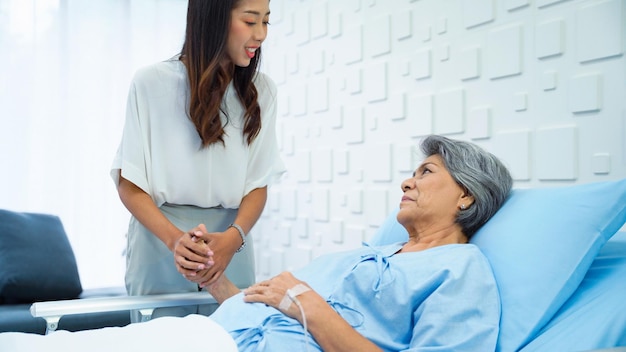 Young woman holding hands to support Sick mother receiving saline in bed in the hospital room