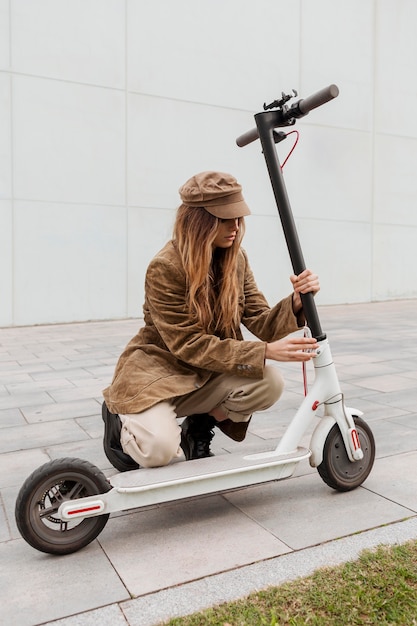 Young woman holding her electric scooter