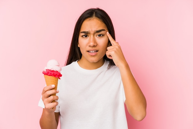 Young woman holding a ice cream showing a disappointment gesture with forefinger.