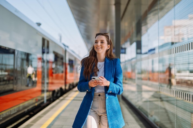 Young woman holding mobile in a train station Commuting to work Public transport concept